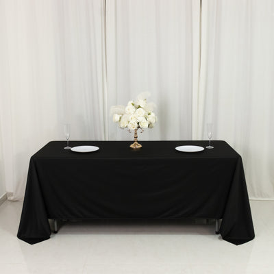 Elegant black table with floral centerpiece and plates set for dining.