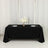 Elegant black table with floral centerpiece and plates set for dining.