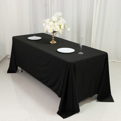 Elegant black tablecloth styled with plates and floral centerpiece.