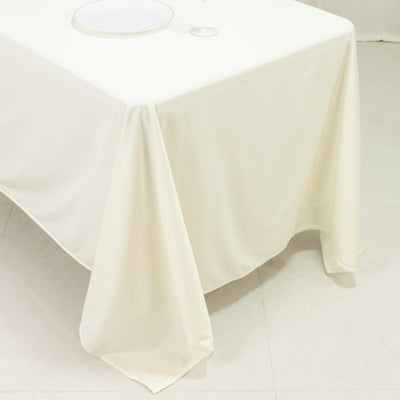 Cream tablecloth draped over a table with a plate and wine glass on top.
