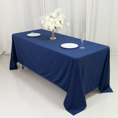 Navy tablecloth with white plates and floral centerpiece on a table.
