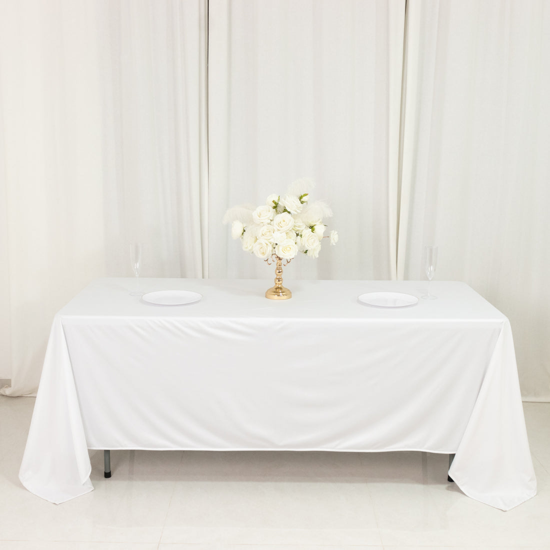 Elegant table setup with white tablecloth and floral centerpiece.