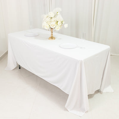 Elegant white table setup with floral centerpiece and plates.