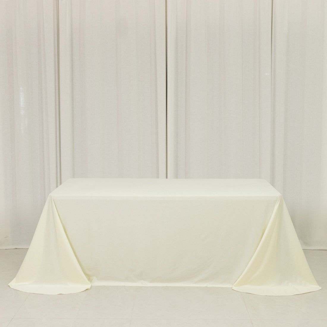 Plain white table with a cream-colored tablecloth draped elegantly.