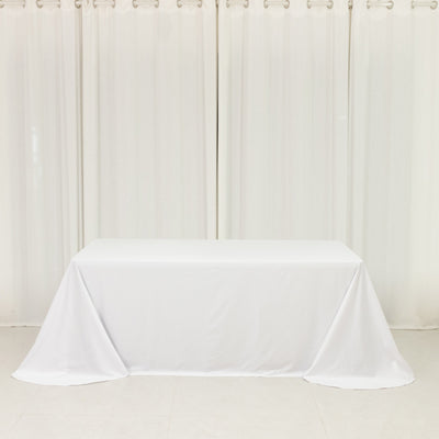 White table covered with a draped cloth in a bright, minimalistic setting.