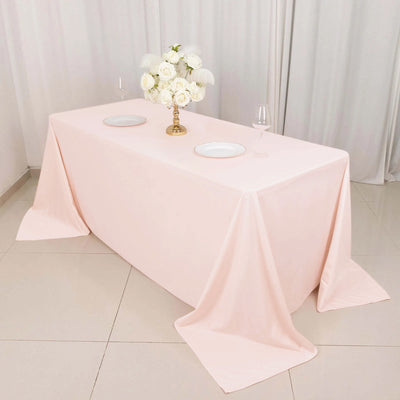 Pink tablecloth draped over a table with decorative flowers and tableware.