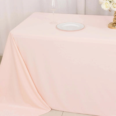 Pink tablecloth draped over a table with a plate and glass on top.