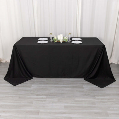 Black tablecloth draped over a table with decorative plates and candles.