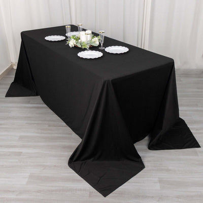 Black tablecloth draped over a dining table with plates and decorative centerpieces.