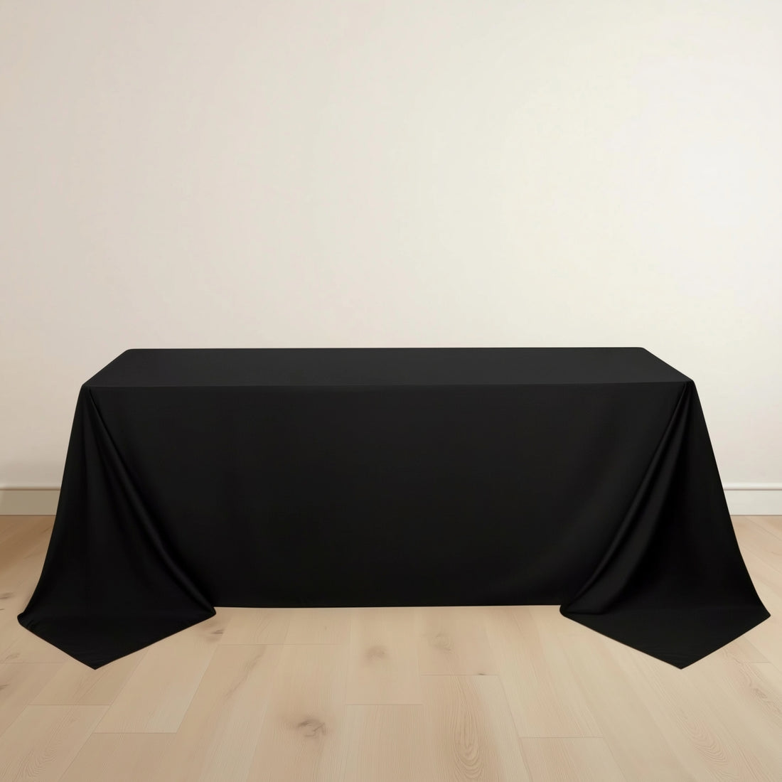 Black tablecloth draped over a rectangular table on a light wooden floor.