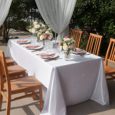 Elegant outdoor dining setup with a sparkling tablecloth and floral centerpieces.