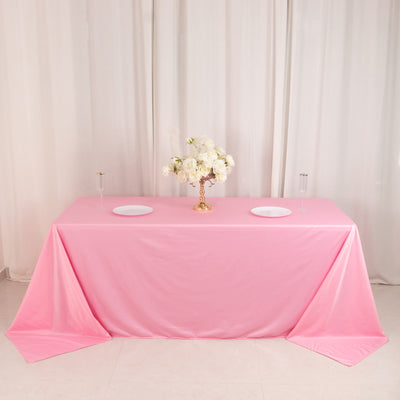 Pink tablecloth draped on a table with floral centerpiece and plates.