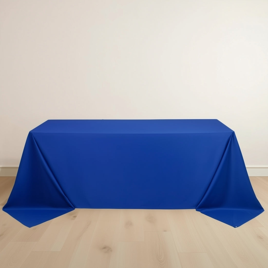 Blue tablecloth draped over a rectangular table on a plain backdrop