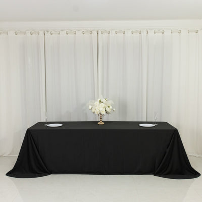 Black tablecloth with floral centerpiece and glassware in a staged setting.