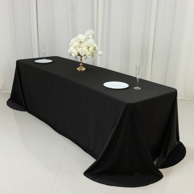 Elegant black tablecloth set for an event with floral centerpiece and dinnerware.