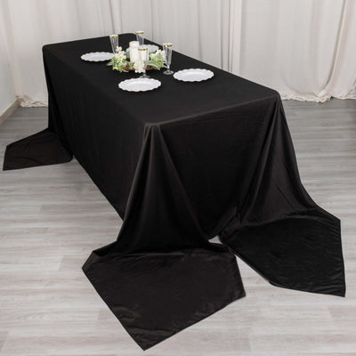 Black tablecloth draping elegantly over a rectangular table with decorative plates.