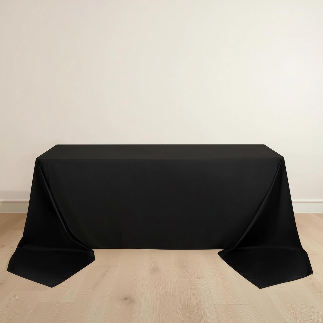 Black tablecloth draped over a table on a light wooden floor.