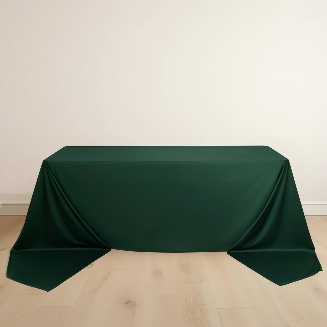 Green tablecloth draped over a table on a light wooden floor.