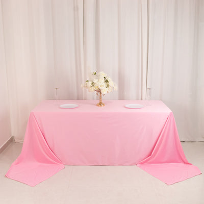 Pink tablecloth with a centerpiece and plates set for a dining arrangement.