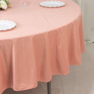 Peach tablecloth draped over a round table with white plates