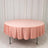 Round pink tablecloth draped over a table in a studio setting.