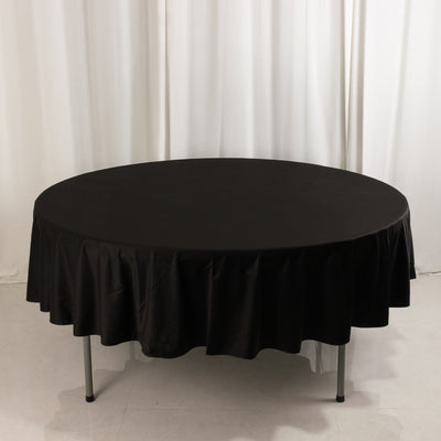 Round black tablecloth draped over a circular table in a studio setting.