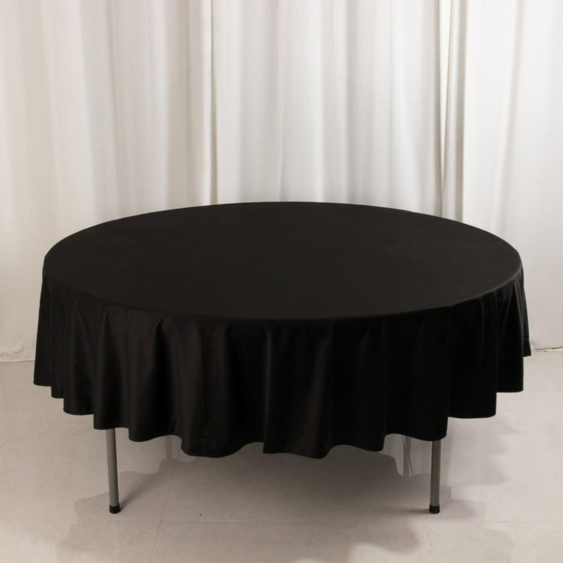 Round black tablecloth draped over a table in studio setting