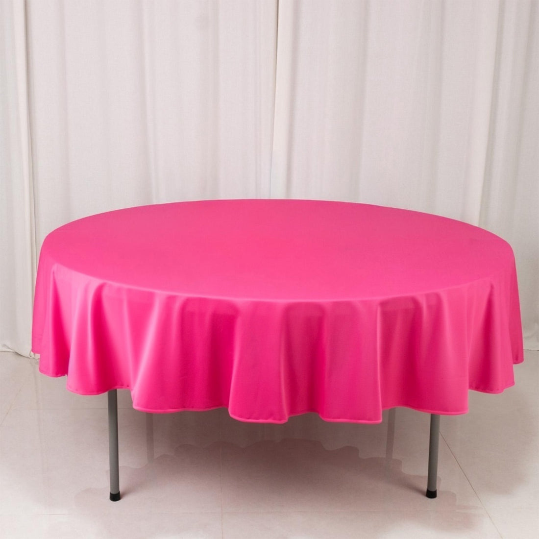 Round pink tablecloth draped over a table in a studio setting.