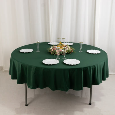 Round green tablecloth with white plates and floral centerpiece.