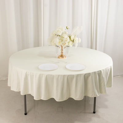 Elegant round table with a cream tablecloth and floral centerpiece.