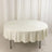 Round table with a cream-colored tablecloth on a plain backdrop