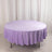 Lavender round tablecloth on a table against a plain backdrop