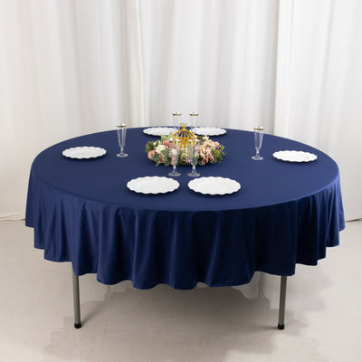 Round navy tablecloth with white plates and floral centerpiece on a table.