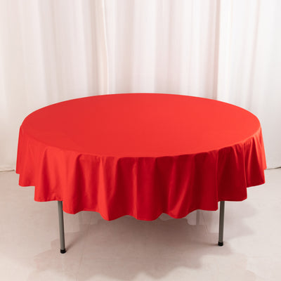 Round red tablecloth on a table with a smooth white backdrop
