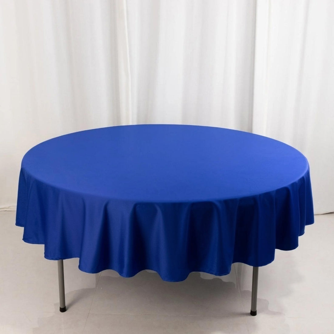 Round blue tablecloth on a table in a studio setting.