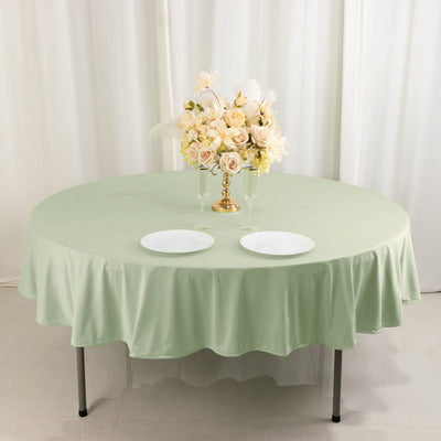 Round green tablecloth with white plates and floral centerpiece