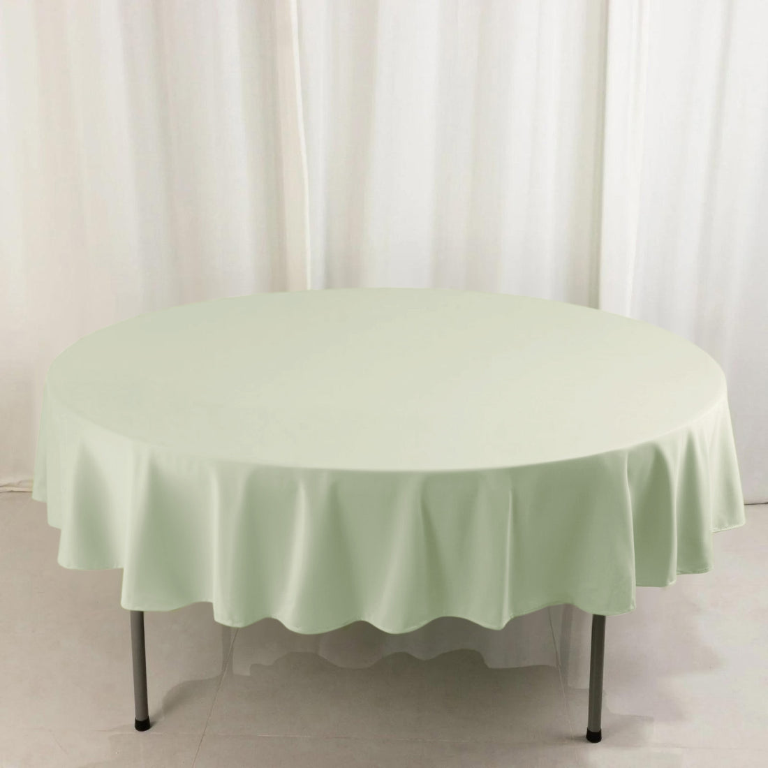 Round mint green tablecloth on a plain backdrop