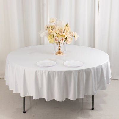 Elegant round table set with white tablecloth and floral centerpiece.