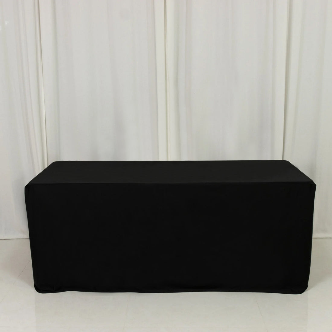 Black table cover draped over a rectangular table in studio setting.