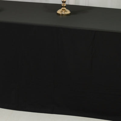 Black tablecloth draped over a table with a decorative lamp