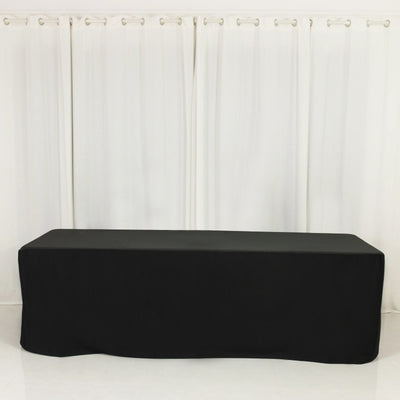 Black fitted table cover on a plain backdrop.