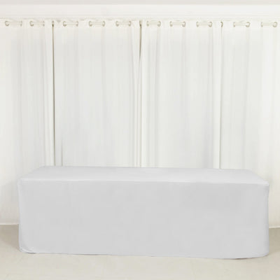 White table cover draped over a rectangular table in a bright room.