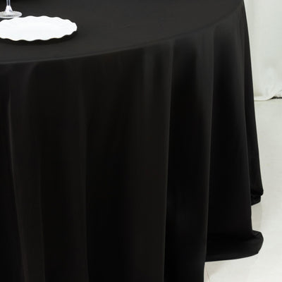 Elegant black tablecloth draping over a round table with a white plate.