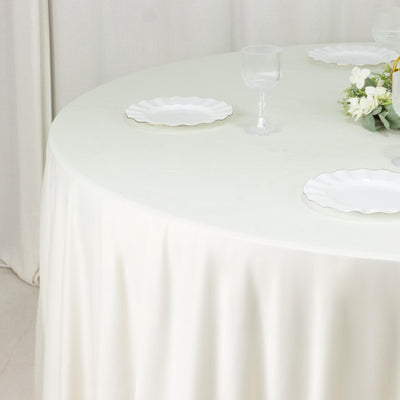 Round table set with white plates and floral centerpiece on a draped tablecloth.