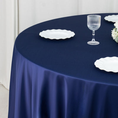 Navy round tablecloth styled with plates and glass in a white room