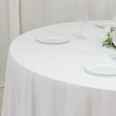 White round table set with elegant plates and glassware for a dining experience.