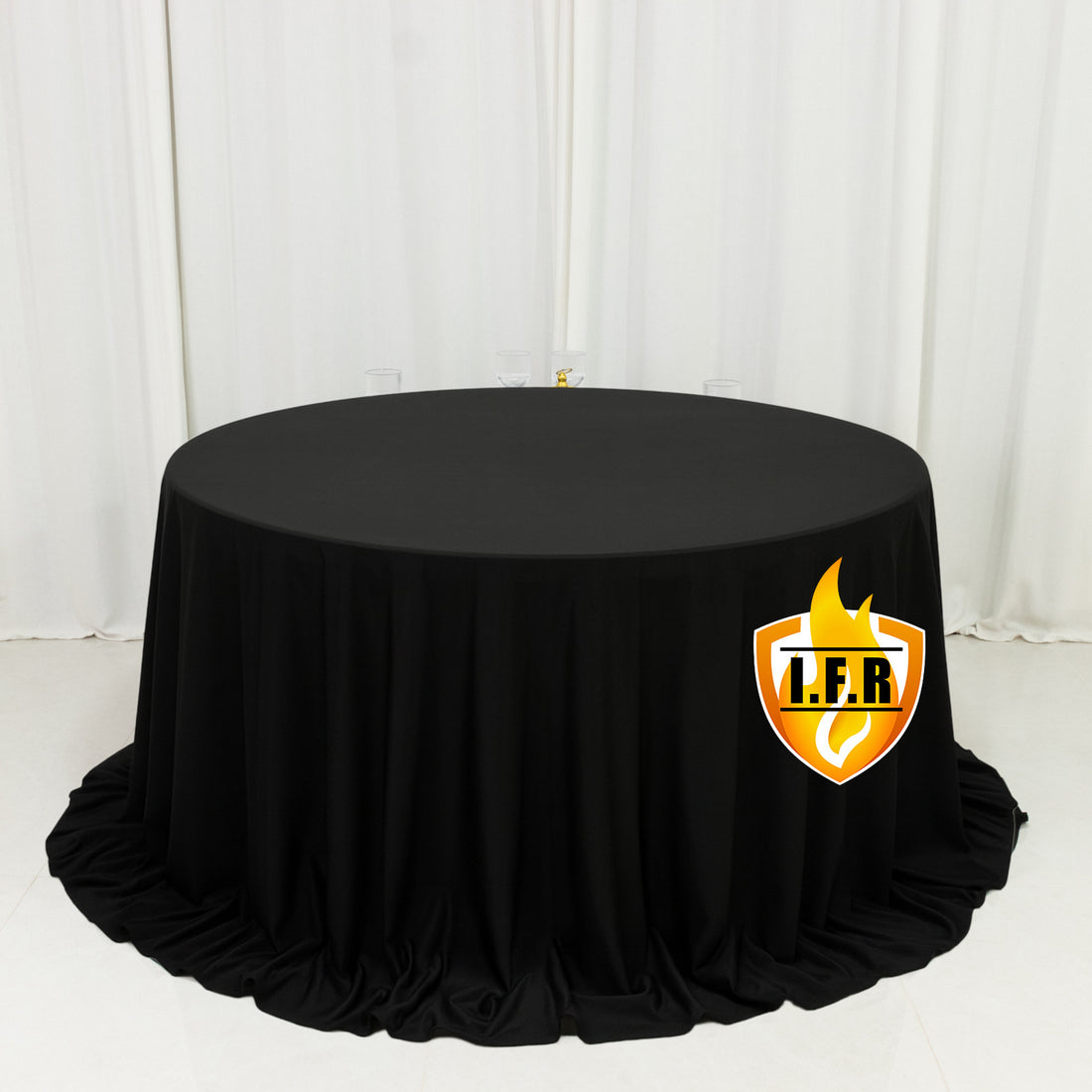 Black round tablecloth on draped table in white room