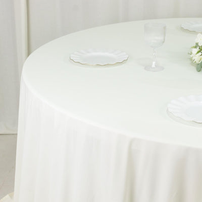 White round tablecloth styled on dining table with plates and glass
