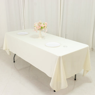 Elegant cream tablecloth draped over a table set for dining with floral centerpiece.