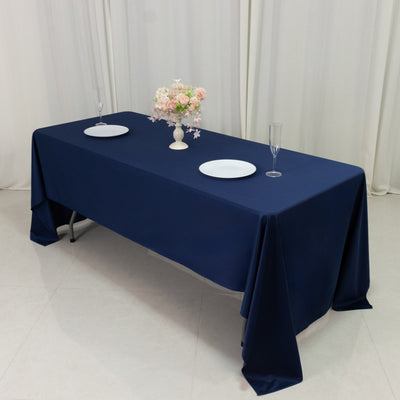 Elegant navy tablecloth draped on a dining table with plates and floral centerpiece.